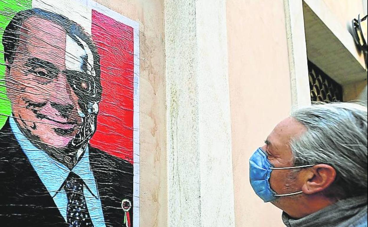 Un ciudadano observa un cartel del veterano Silvio Berlusconi.