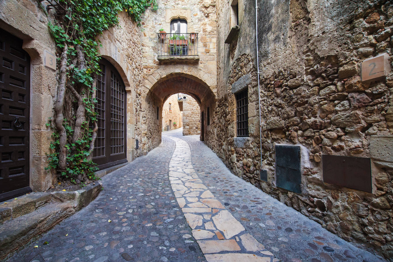 Pals (Cataluña). El pueblo de Pals, ubicado en la comarca del Baix Empordà, es uno de los más bonitos de la Costa Brava (Girona, Cataluña). Esta pequeña villa medieval suele recibir un buen número de turistas cada fin de semana. Aunque no tiene monumentos o museos de gran renombre, sus preciosas calles empedradas, sus murallas y sus edificios góticos son un reclamo más que suficiente para justificar una visita. El topónimo de Pals tiene su origen en el nombre latino Palus (lugar pantanoso). El pueblo, junto a su castillo de Montaspre (montis aspero), se menciona por primera vez en el año 889 en un precepto del rey Odón de Francia. Durante siglos, diferentes reyes cedieron el castillo y la villa a los obispos de Girona, a diversas familias nobles, a los condes de Barcelona, a los barones de Cruïlles, etc. Durante la guerra civil catalana el castillo quedó destruido y hoy solo se conservan la Torre de les Hores, las murallas y algún elemento estructural.