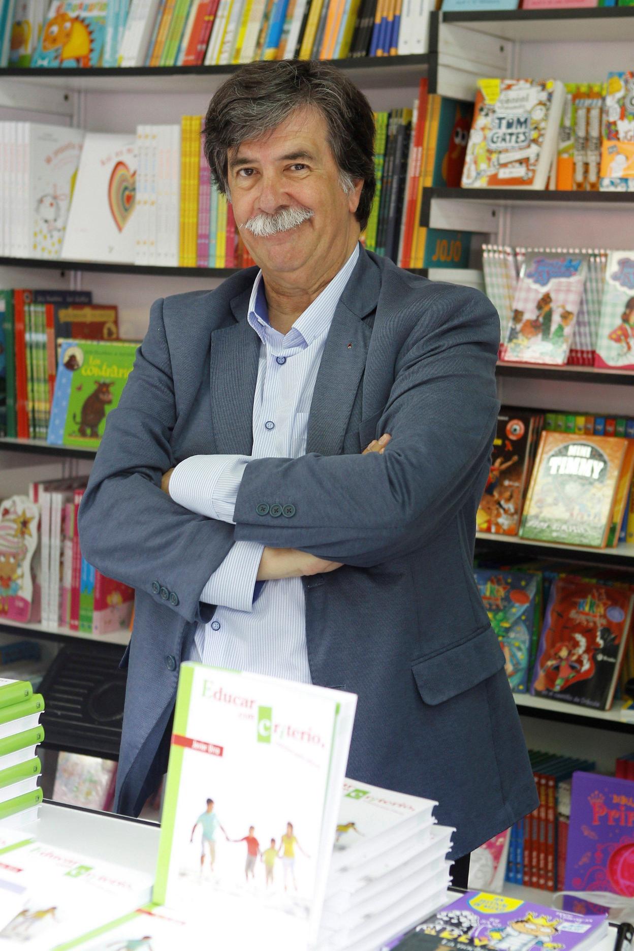 Javier Urra posa frente a una estantería con libros para pequeños. 