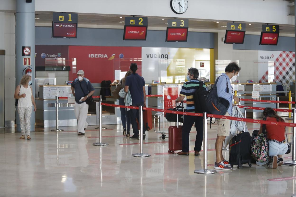 Pasajeros hacen cola para facturar y embarcar en su vuelo en el aeropuerto de Asturias. 