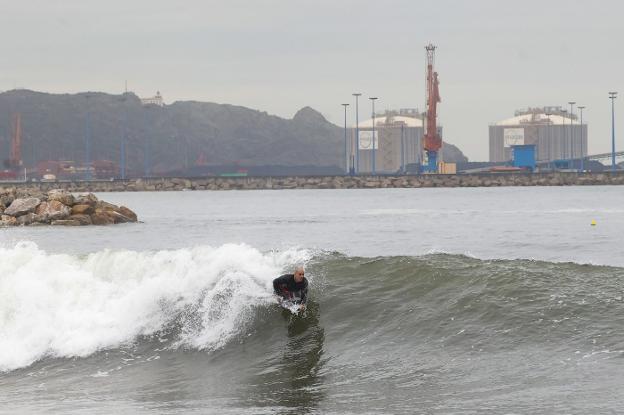 Un surfista practica su deporte en la playa de Poniente. 