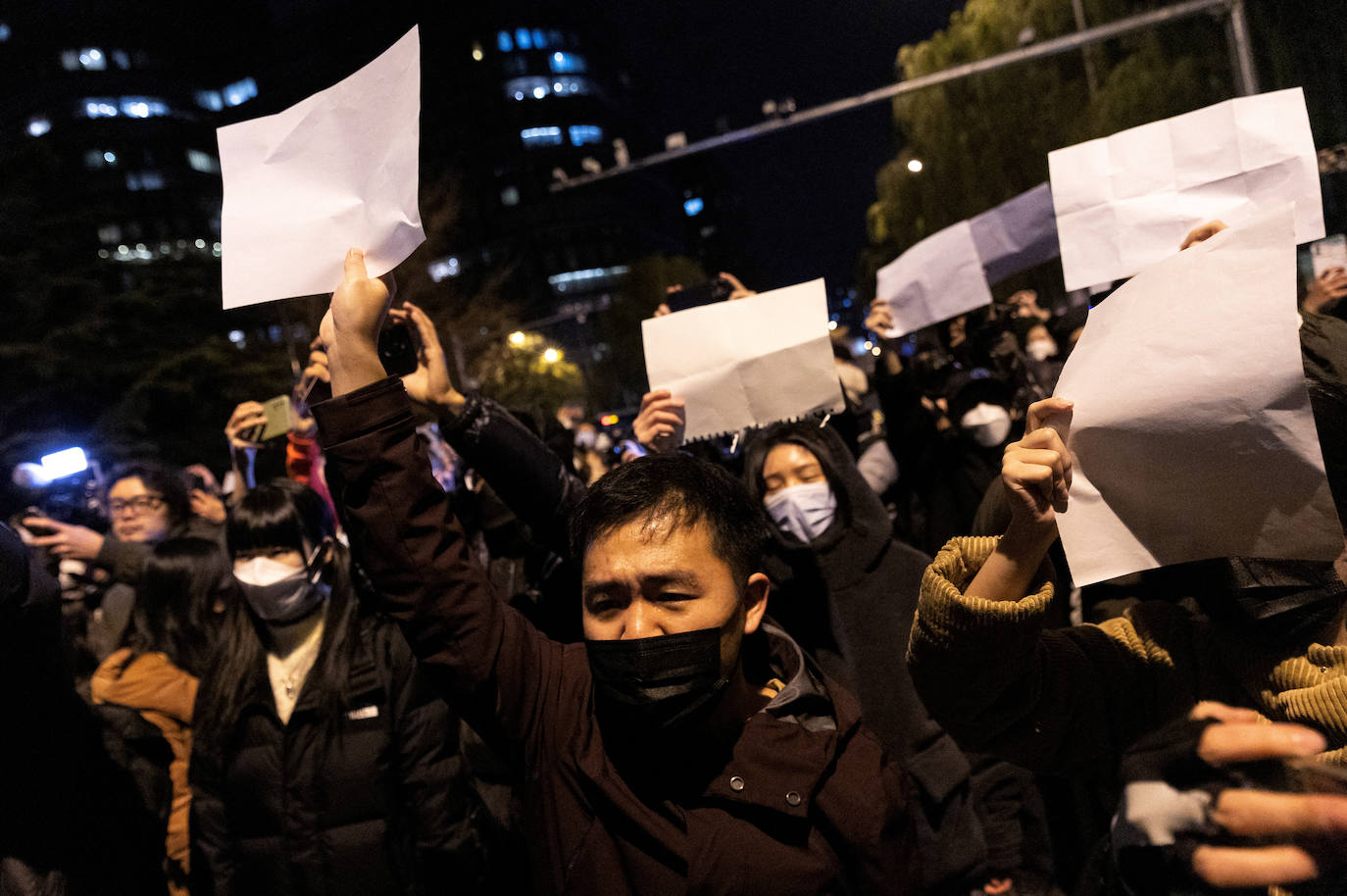 Los manifestantes sostienen hojas blancas en protesta por las restricciones a la enfermedad por coronavirus (COVID-19) en Beijing, China.