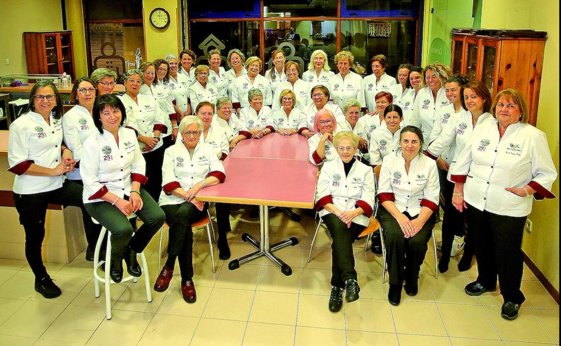 LAS MAESTRAS DE LOS FOGONES. Por la izquierda, de pie, Herminia (Casa Nuevo), Primi (Casa Pepe), Nieves (La Casona de Mestas), Aurora (Teyka), Ángela (Casa Emburria), Rosamari (La Mayacina), Mayte y Blanca (Casa Lula), Teresa (Casa Maravillas), Pili (Los Pomares), Isabel (La Tenada), Mari (El Fartuquín), Mary (Mesón El Centro), Carmen (La Posada de San Blas), Teresa (Bar Camacho), Mayte (La Costana), Anafé (El cenador del azul), Luisa (Casa Ricardo), Annalisa (Taberna Salcedo), Noelia (Los Pisones), María (Casa Eutimio), Ramona (Casa Belarmino) y Mari Carmen (Villa Blanca). Sentadas, de derecha a izquierda, Ivonne (Casa Telva), Aida Rosales (Casa Eutimio), Sara López (Casa Telva), Viri (El Llar de Viri), Beatriz (Los Pisones), Joaquina (El Cordial-Casa Chema), Amada (presidenta), Gloria (El Panduku), Teté y Paloma (Casa Zoilo), Lola (Yumay), Tinina (La Xungueira) y Lydia (Casa Mon's).