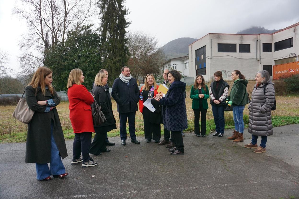 Políticos y miembros de la comunidad educativa visitaron el solar que albergará el nuevo bloque del IES Rey Pelayo de Cangas de Onís. El presidente Adrián Barbón escribe su felicitación de Año Nuevo en la pizarra de una clase, bajo la atenta mirada de la diputada Gimena Llamedo. 