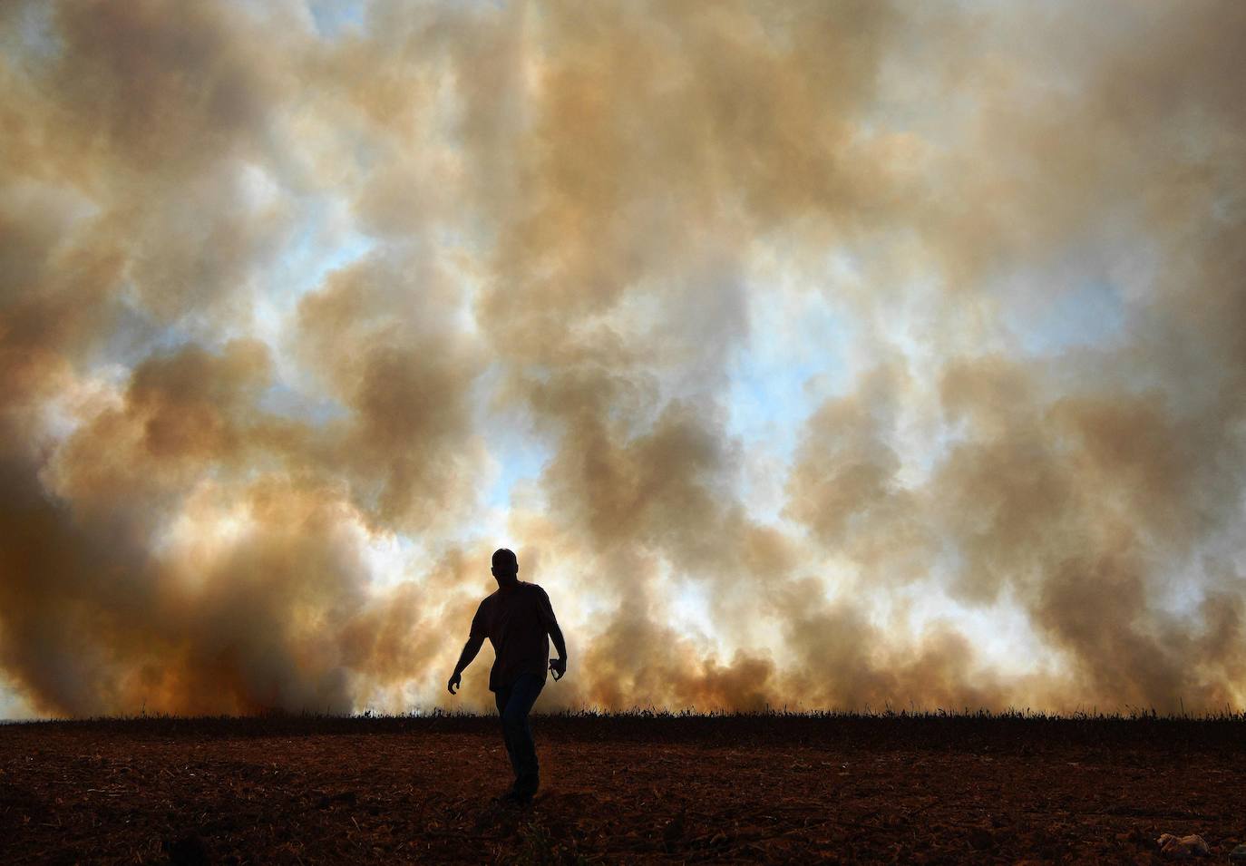 Un hombre frente al humo que sale de un fuego intencionado en un campo de maíz que bordea una reserva de selva tropical, en Sinop, estado de Mato Grosso, Brasil, el 9 de agosto de 2020.