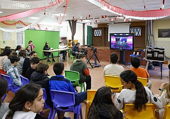 Los alumnos presencian la grabación del informativo de televisión en el salón de actos del colegio, convertido en un plató por una mañana.
