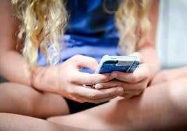 Una mujer, tecleando en su teléfono móvil.