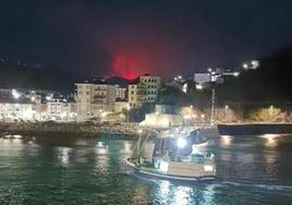 Desde el muelle de Luarca, el fuego se asoma en Aristébano.