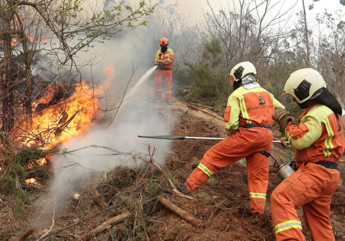 Tres bomberos de Asturias, tratando de mantener a raya una lengua de fuego en Tineo.