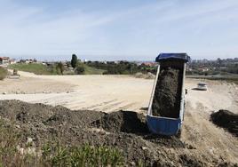 Un camión descargando tierra de la obra de ampliación hospitalaria en la finca municipal de Tremañes.