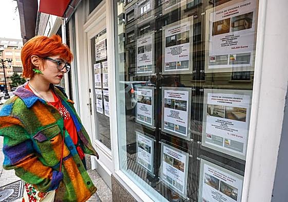 Una joven observa los anuncios de alquiler de pisos en una agencia inmobiliaria en Oviedo.