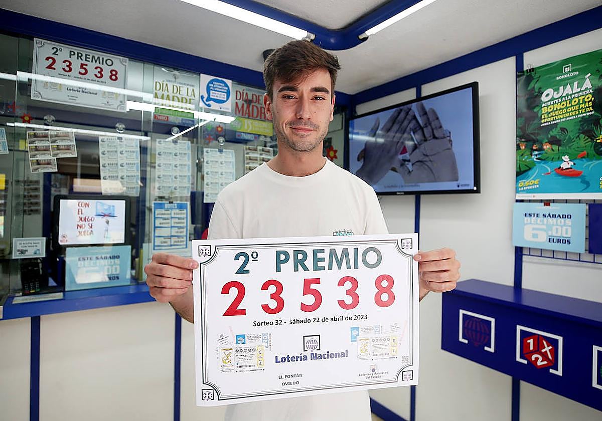 El lotero de la administración ovetense número 21 de la calle Fierro posa con el cartel del número dotado con el segundo premio de la Lotería Nacional.