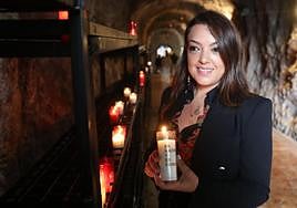 Carolina López coloca una vela encendida como ofrenda a la entrada de la Cueva de Covadonga.