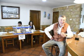 Un cliente disfruta de un vino en la barra de Casa Mari mientras la mesa electoral espera al próximo votante.