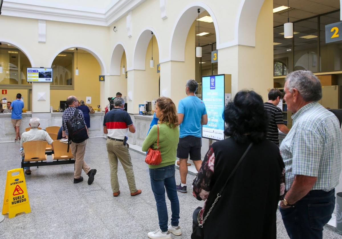 Ciudadanos esperan a ser atendidos en la oficina central de Correos de Gijón.