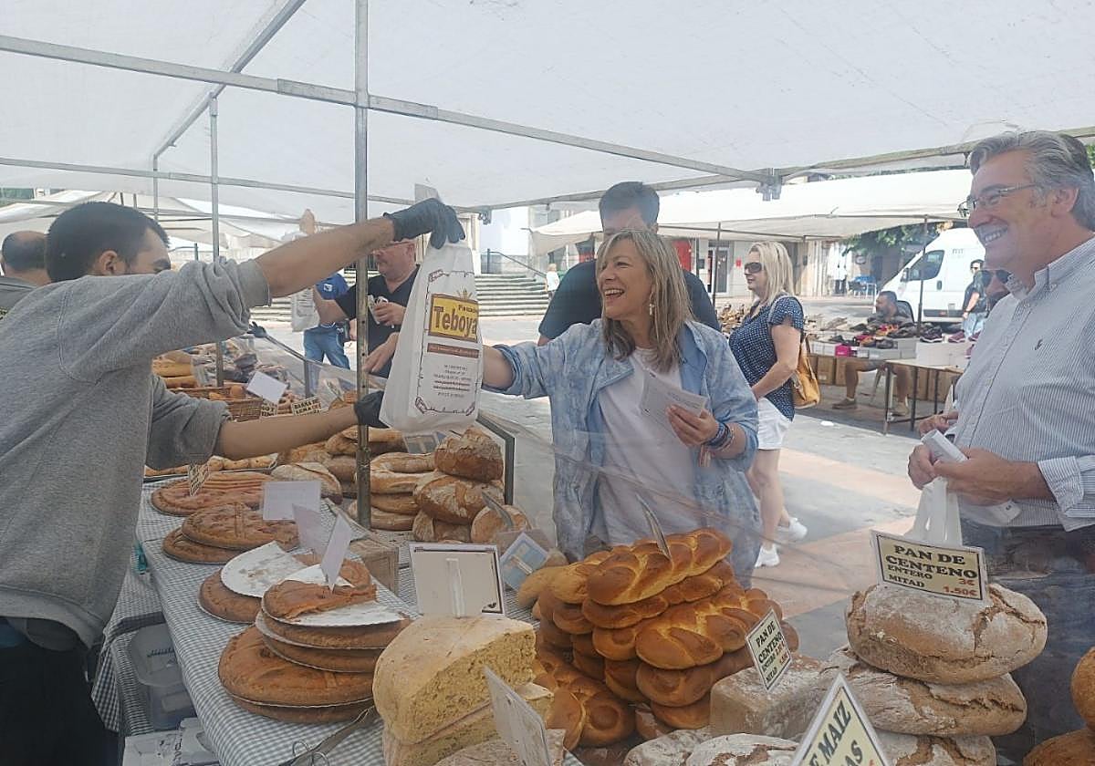 Esther Llamazares compra productos de Panadería Teboyas durante su visita al mercado de Pola de Lena, junto a Pablo González.