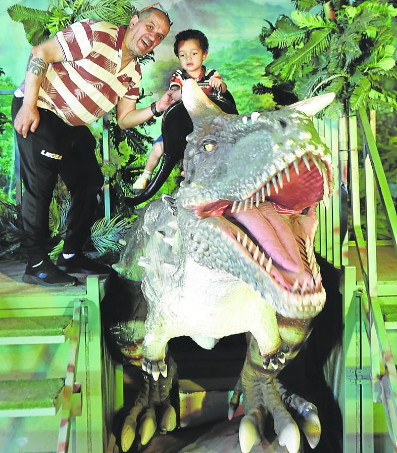 Uno de los niños subido a lomos de un dinosaurio.