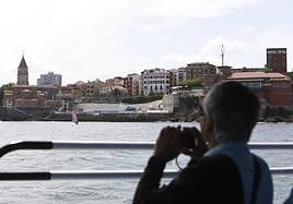 Un turista toma una foto a la Iglesia de San Pedro desde el barco 'Cimavilla I'.