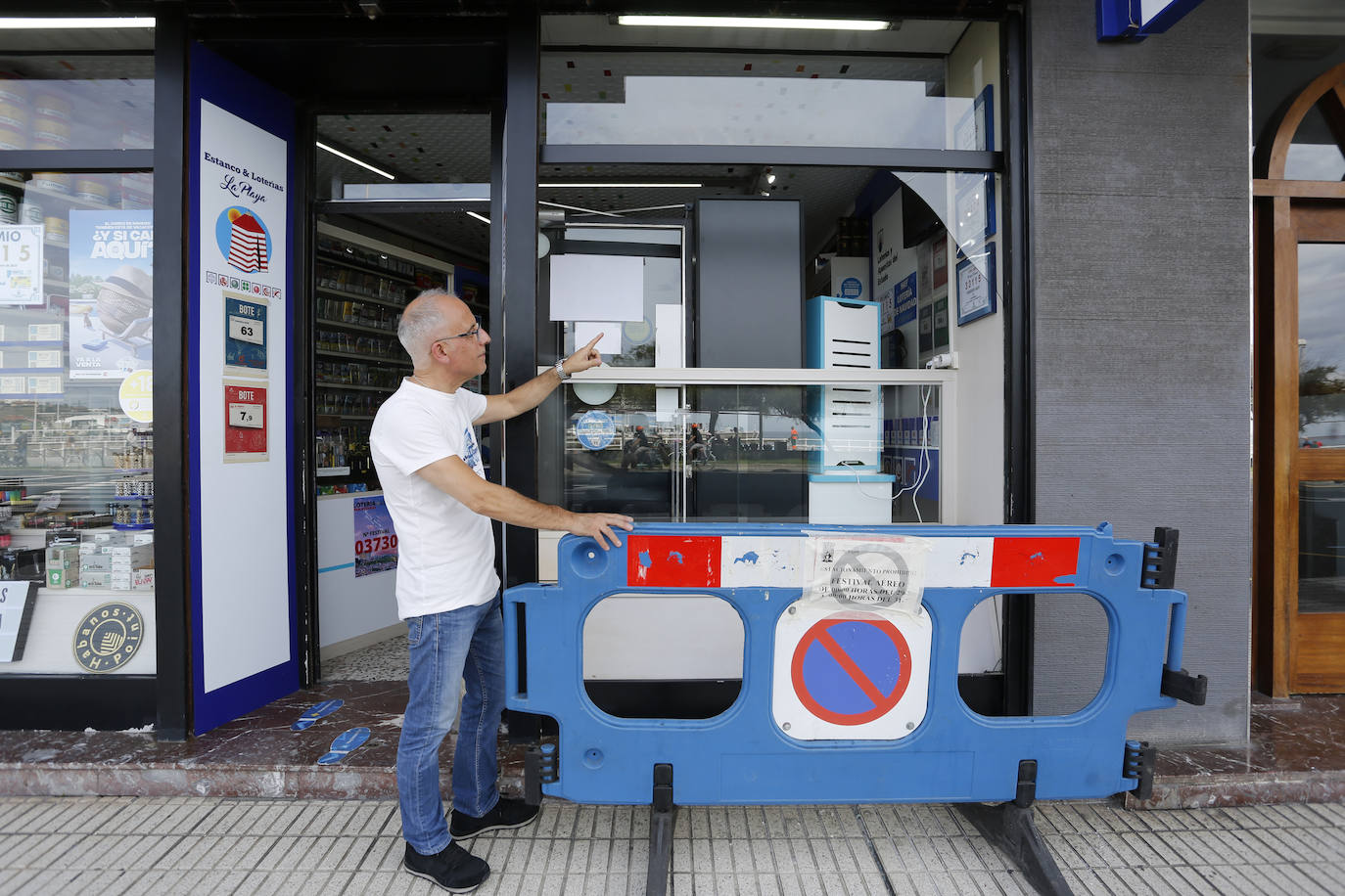El propietario del estanco, Edurardo Fernández, muestra la luna rota en el Muro de San Lorenzo.