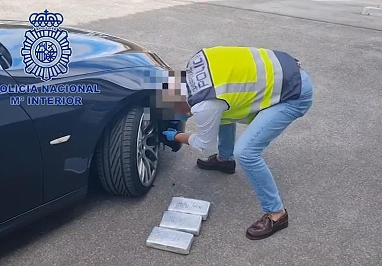 Una agente extrae los fardos de cocaína del hueco de la defensa delantera del turismo.