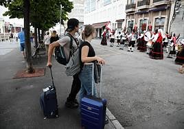 Dos viajeros disfrutando de un desfile en Gijón.