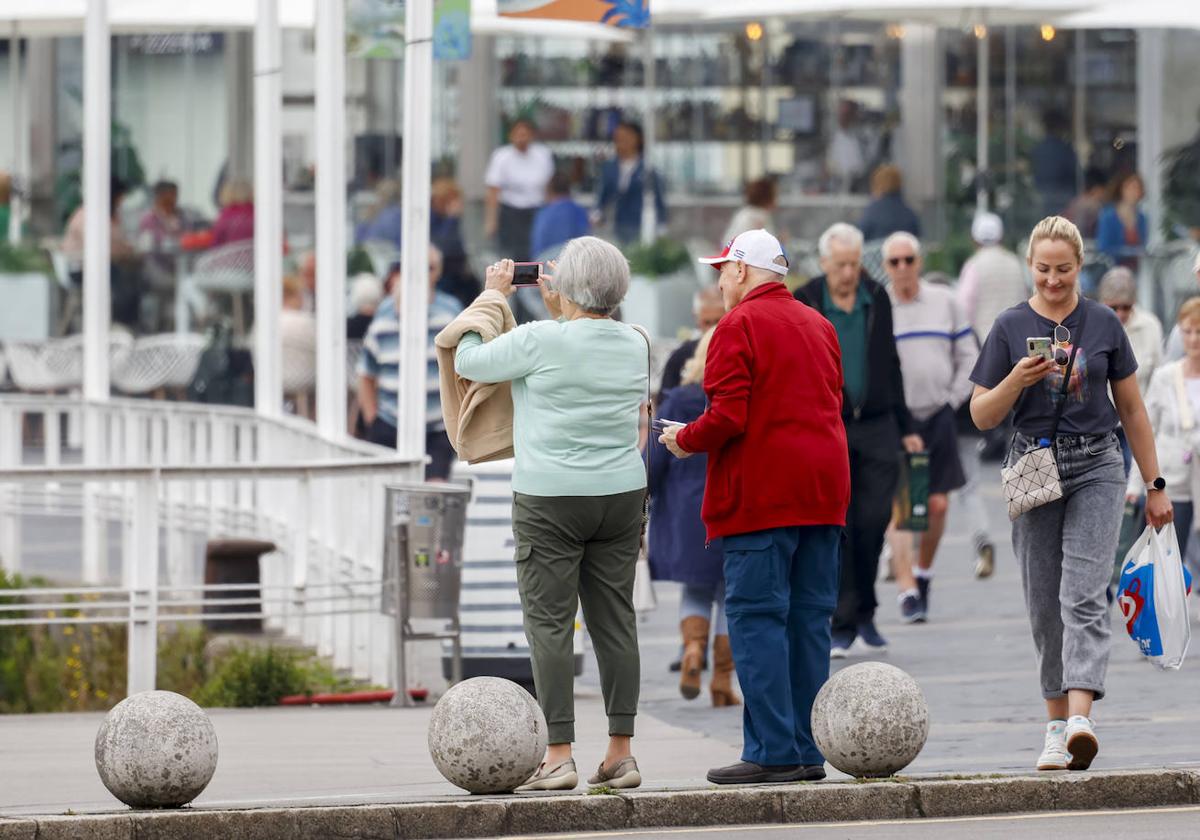 Una pareja de jubilados toma una fotografía en Gijón.