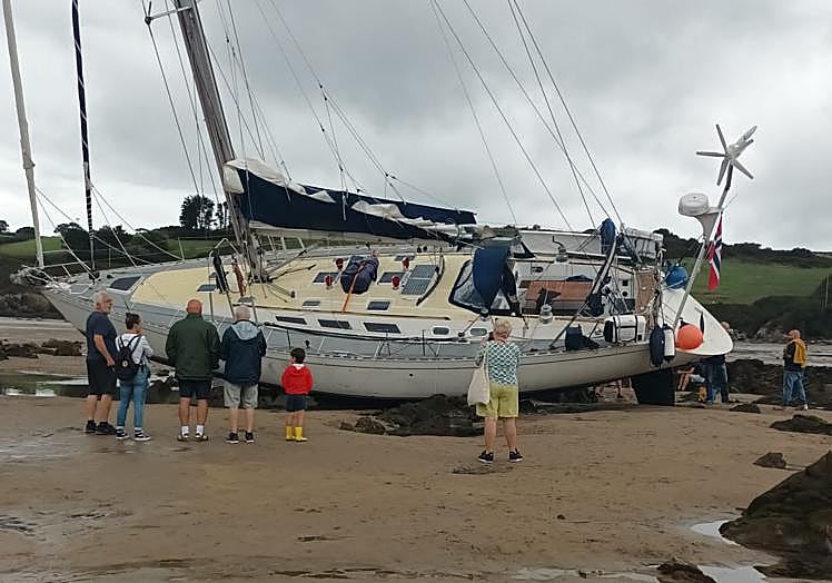 Imagen principal - Un velero vara en la playa de Bañugues a causa de una avería eléctrica