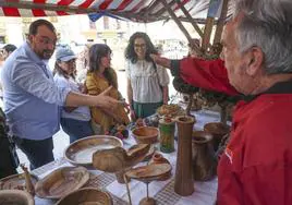 Adrián Barbón saluda a uno de los artesanos del mercado tradicional de Pola de Laviana. A la derecha, Vanessa Gutiérrez .