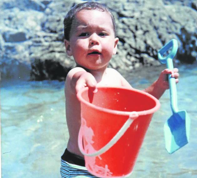 De niño, ofreciendo el cubo de la playa.