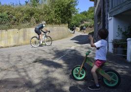 Un niño observa el paso de ciclistas aficionados en el ascenso.