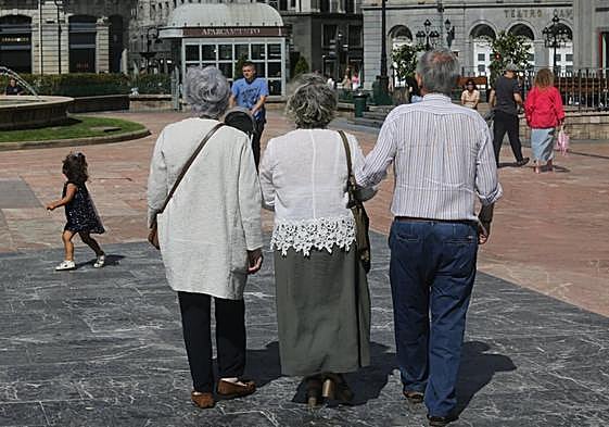 Tres personas mayores pasan junto a una niña en la plaza de la Escandalera, en Oviedo.