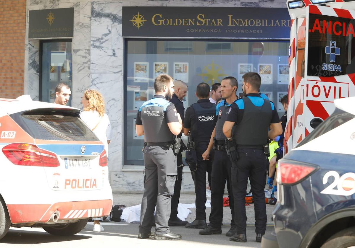 Policías y sanitarios poco después del crimen a las puertas de la inmobiliaria.