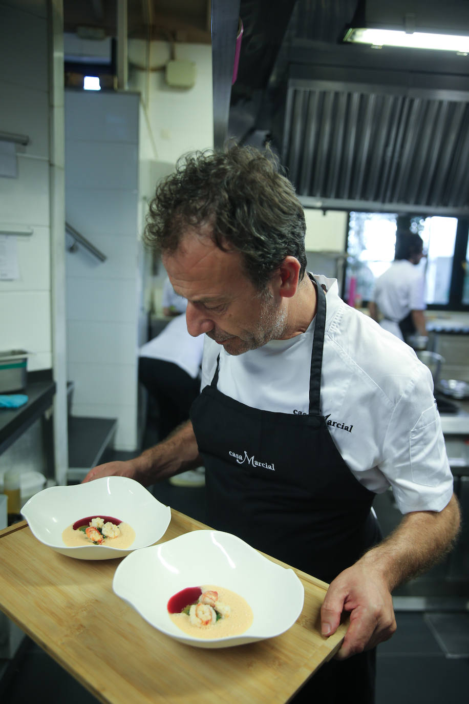 Imagen secundaria 2 -  Arriba, Nacho celebra los 30 años de Casa Marcial con el personal de sala y cocina y con su hermana Esther y su sobrino Chus. Abajo, el chef ultima un servicio en la cocina de su restaurante. 