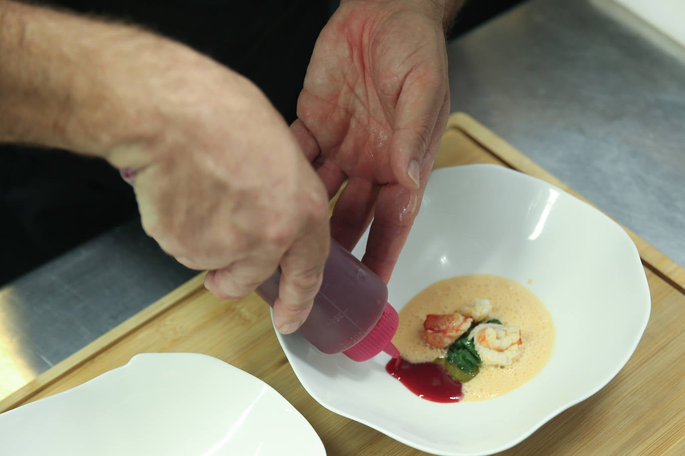 Imagen secundaria 1 -  Arriba, Nacho celebra los 30 años de Casa Marcial con el personal de sala y cocina y con su hermana Esther y su sobrino Chus. Abajo, el chef ultima un servicio en la cocina de su restaurante. 