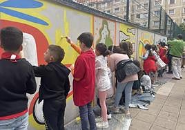 Los alumnos del Aniceto Sela pintan un mural en el exterior del centro escolar.