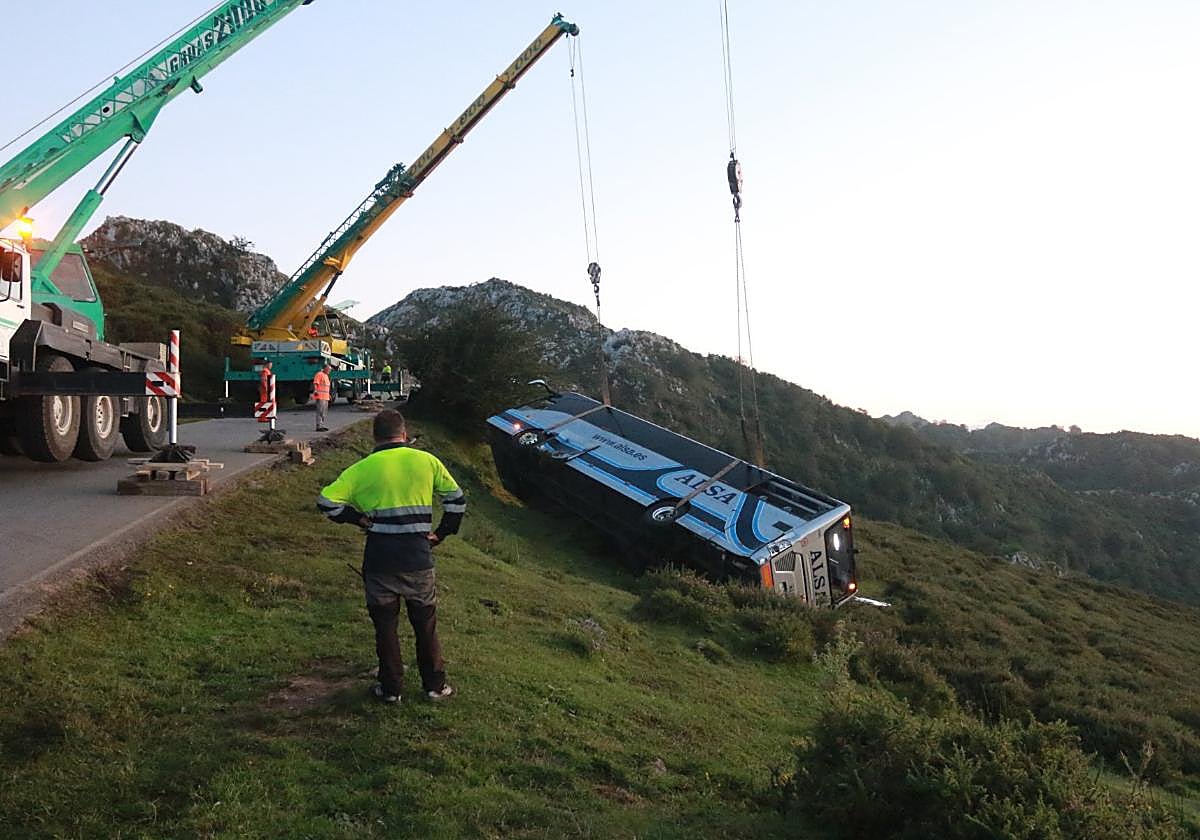 Una grúa recupera el autobús accidentado, que volcó en la zona de El Espinu.