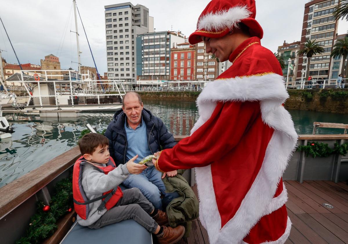 El paje real entrega a un niño el clásico revoltijo navideño antes de zarpar del Muelle.