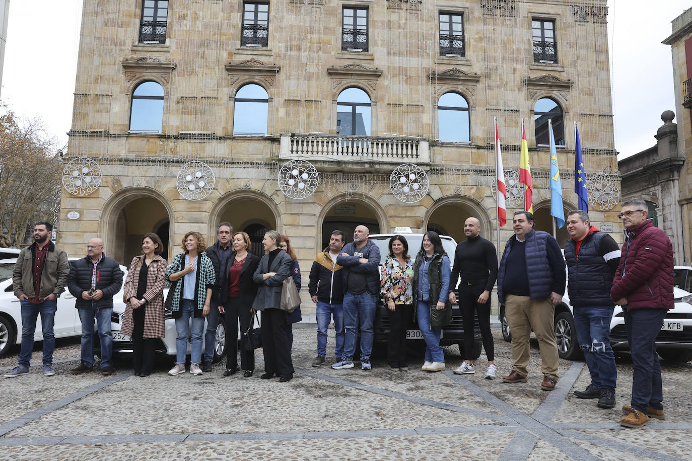 Representantes de las cooperativas del taxi participantes en la iniciativa solidaria posan en la plaza Mayor con el edil Pelayo Barcia.