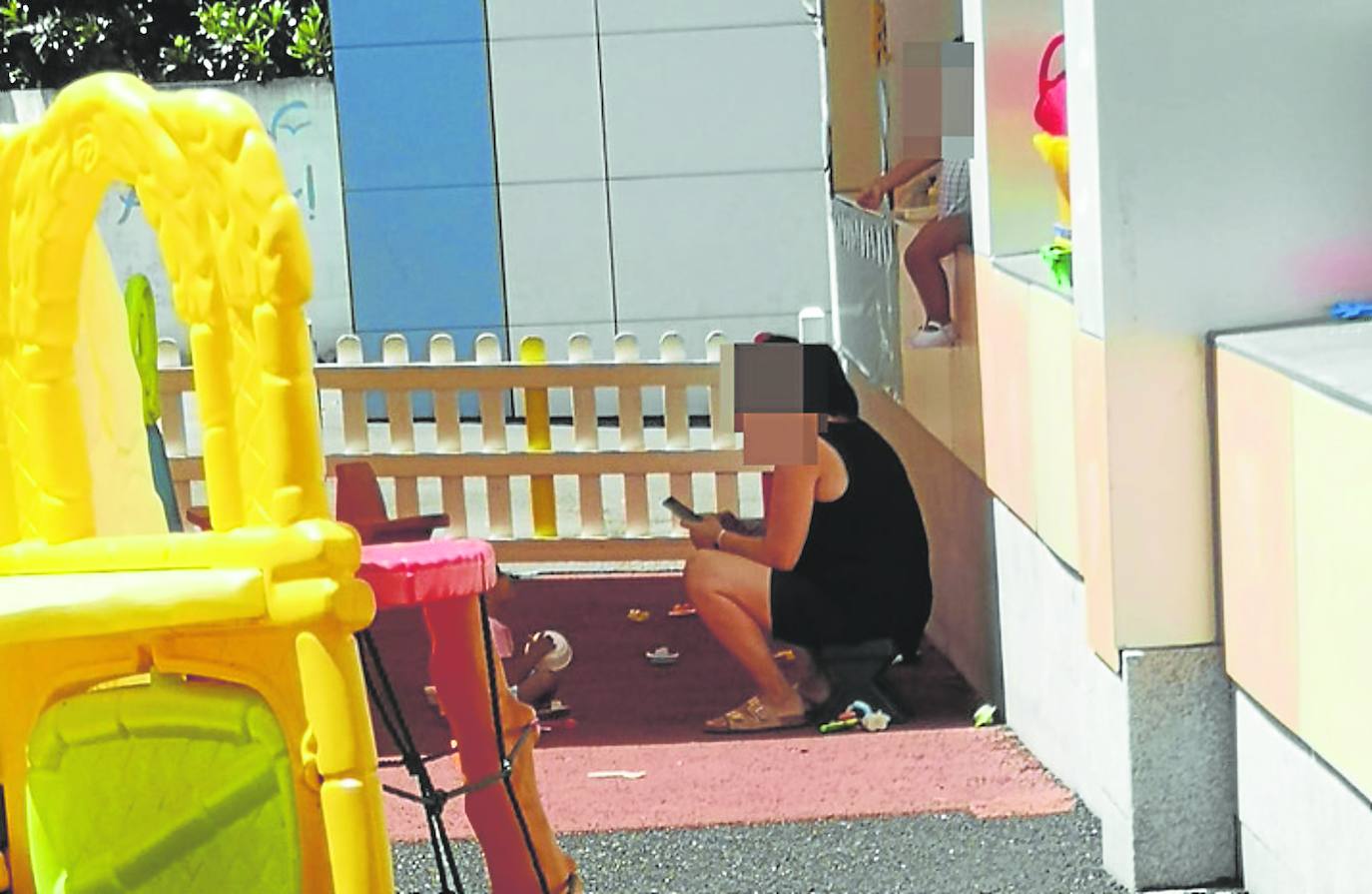 Unas de las fotografías que el extrabajador acompañó en su denuncia. En ella se ve a a un niño en el alféizar de una ventana del patio y a la cuidadora observando el móvil.