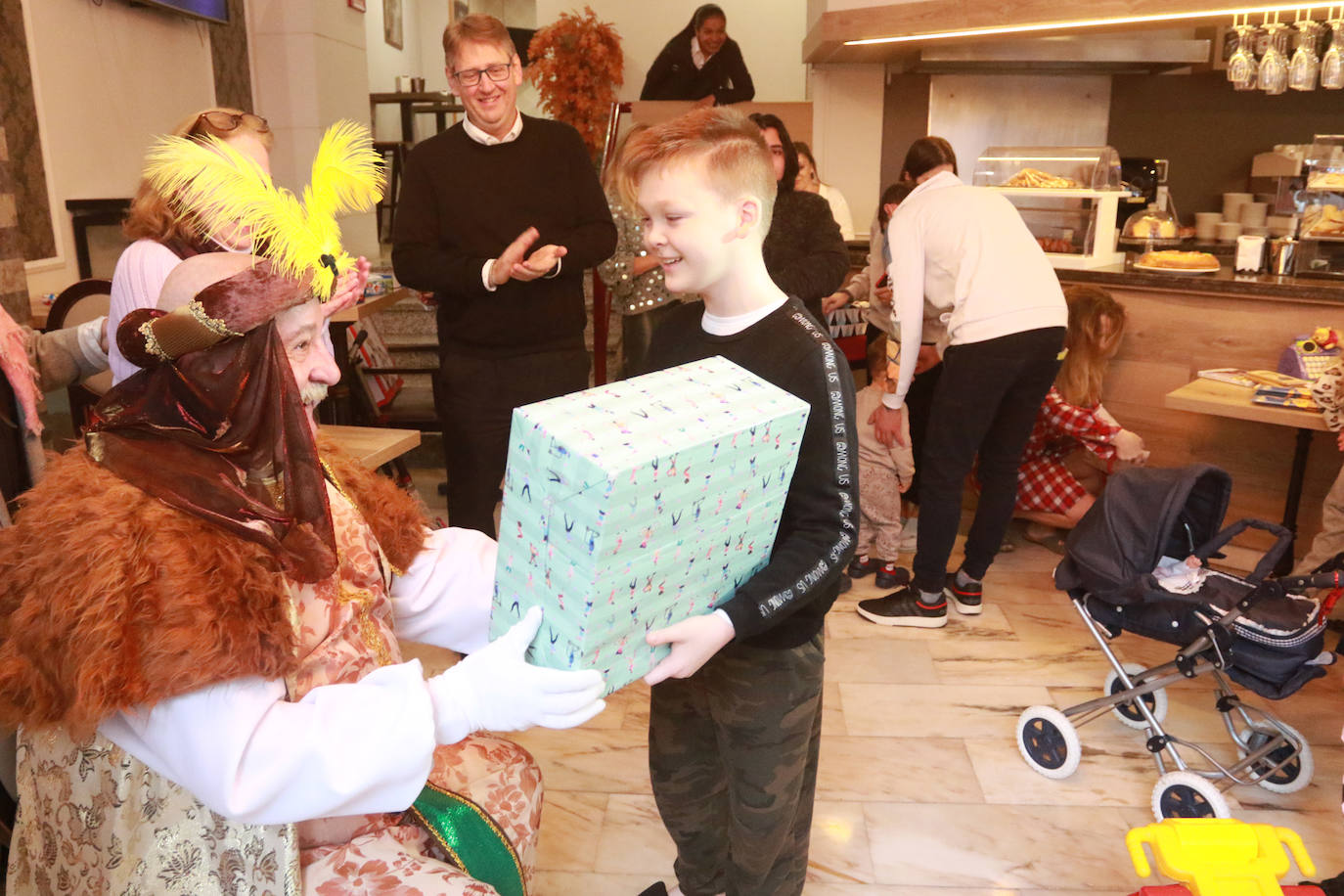 San Nicolás hace entrega de uno de los regalos a un niño ucraniano en el recibidor del hotel Don Manuel.