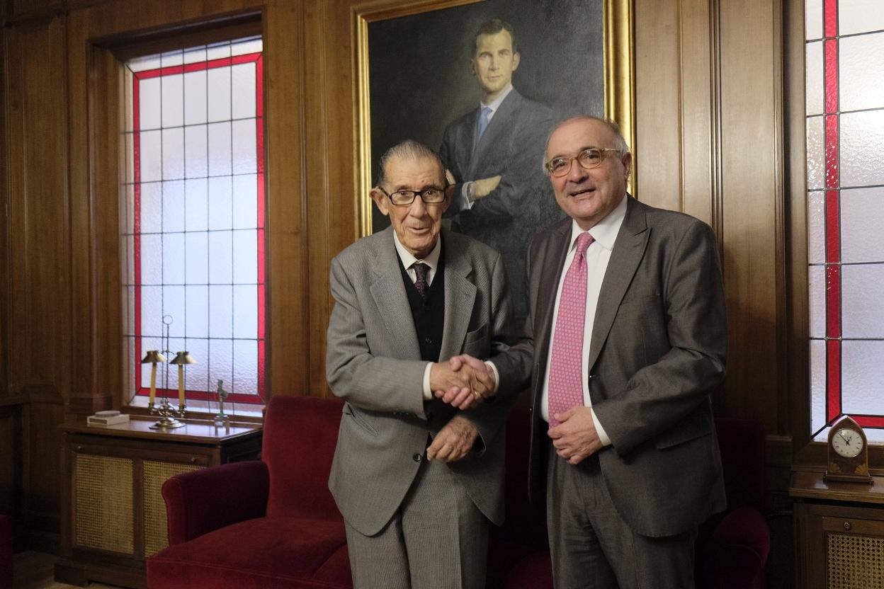 Juan Velarde estrecha la mano a Benigno Pendás, a quien le pasó el testigo como director de los cursos de La Granda. 