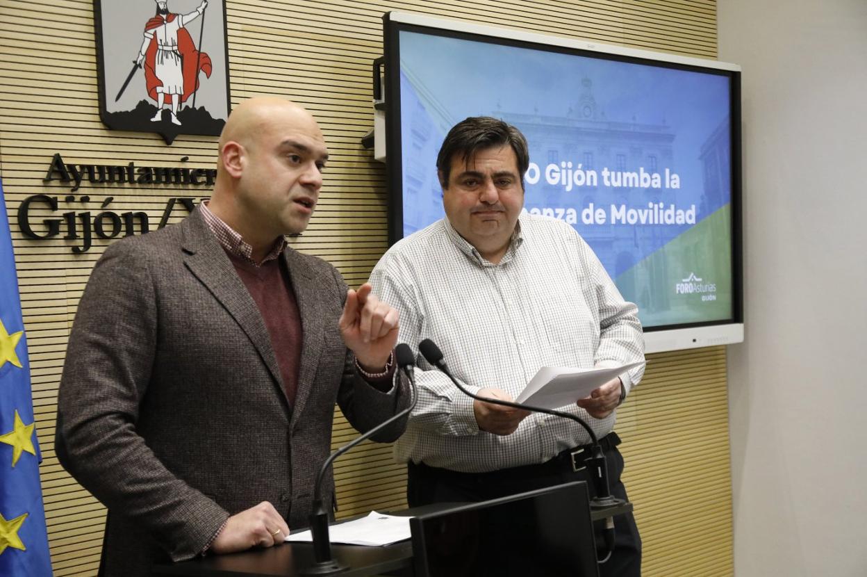 Los ediles Jesús Martínez Salvador y Pelayo Barcia comparecen con una pantalla que pone 'Foro Gijón tumba la Ordenanza de Movilidad'. 