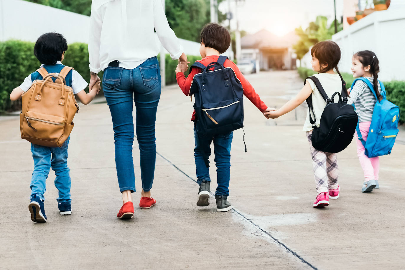 Cuatro niños pasean junto a una mujer de camino al colegio. 