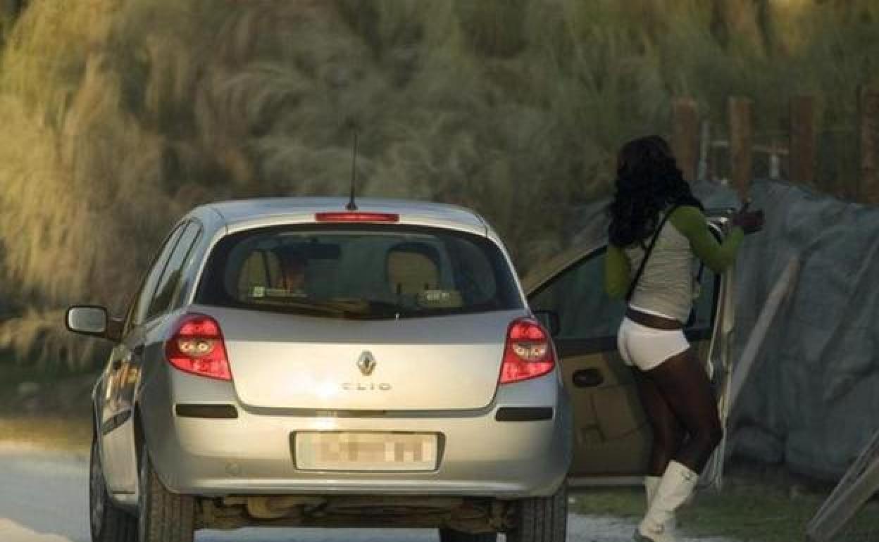 Una prostituta desciende del automóvil de un cliente junto al arcén de una carretera.