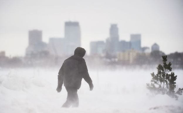 Un hombre camina en por un parque de Minneapolis durante una tormenta de nieve