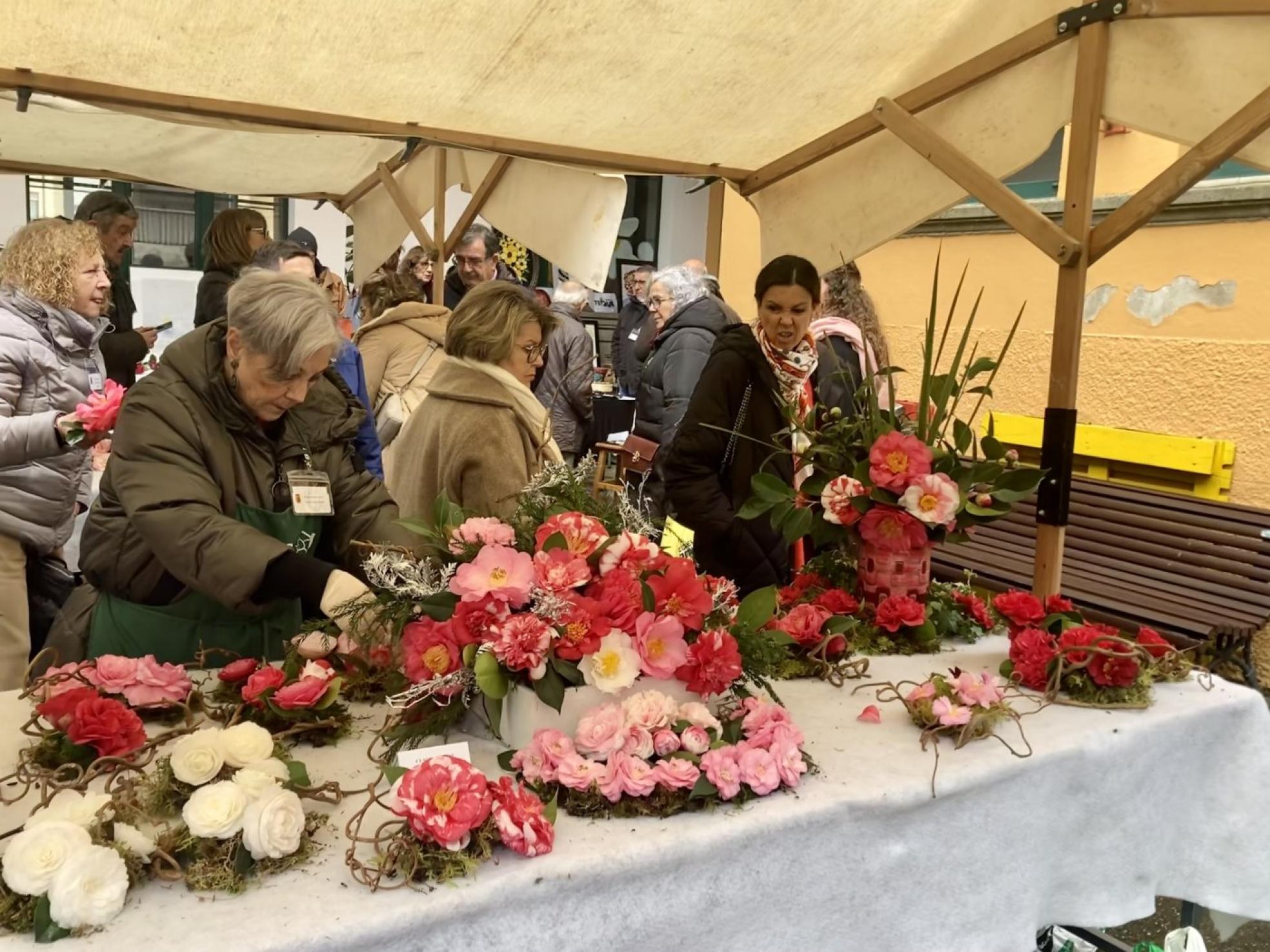 Una mujer coloca uno de los centros de camelias en su puesto de exposición. 