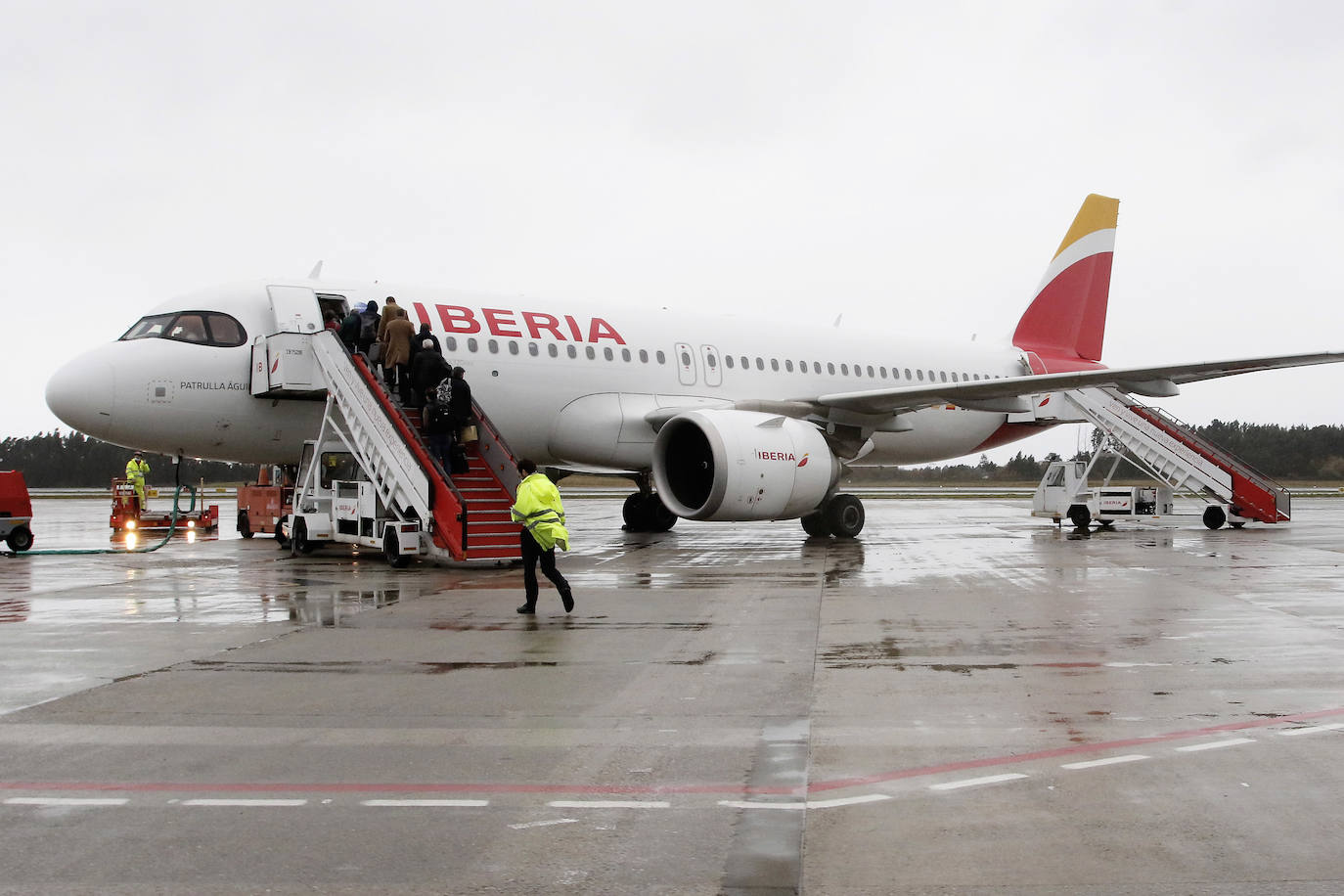 Los pasajeros suben a un avión de Iberia mientras reposta en la pista del aeropuerto de Asturias.