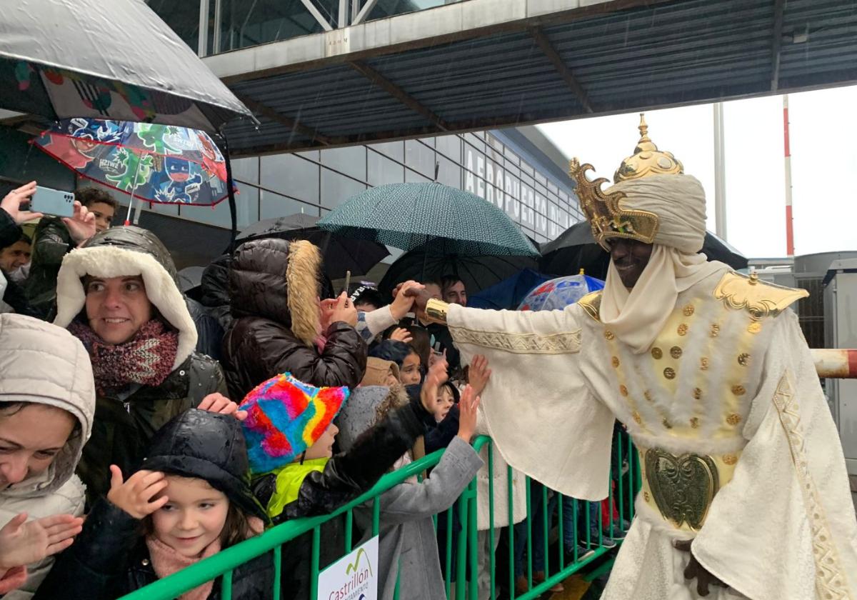 Baltasar saluda a niños y mayores a su llegada al Aeropuerto de Asturias bajo la lluvia.