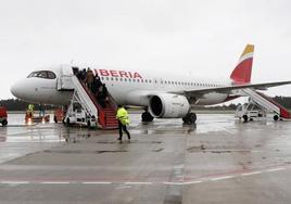 Los pasajeros suben a un avión de Iberia mientras reposta en la pista del aeropuerto de Asturias.