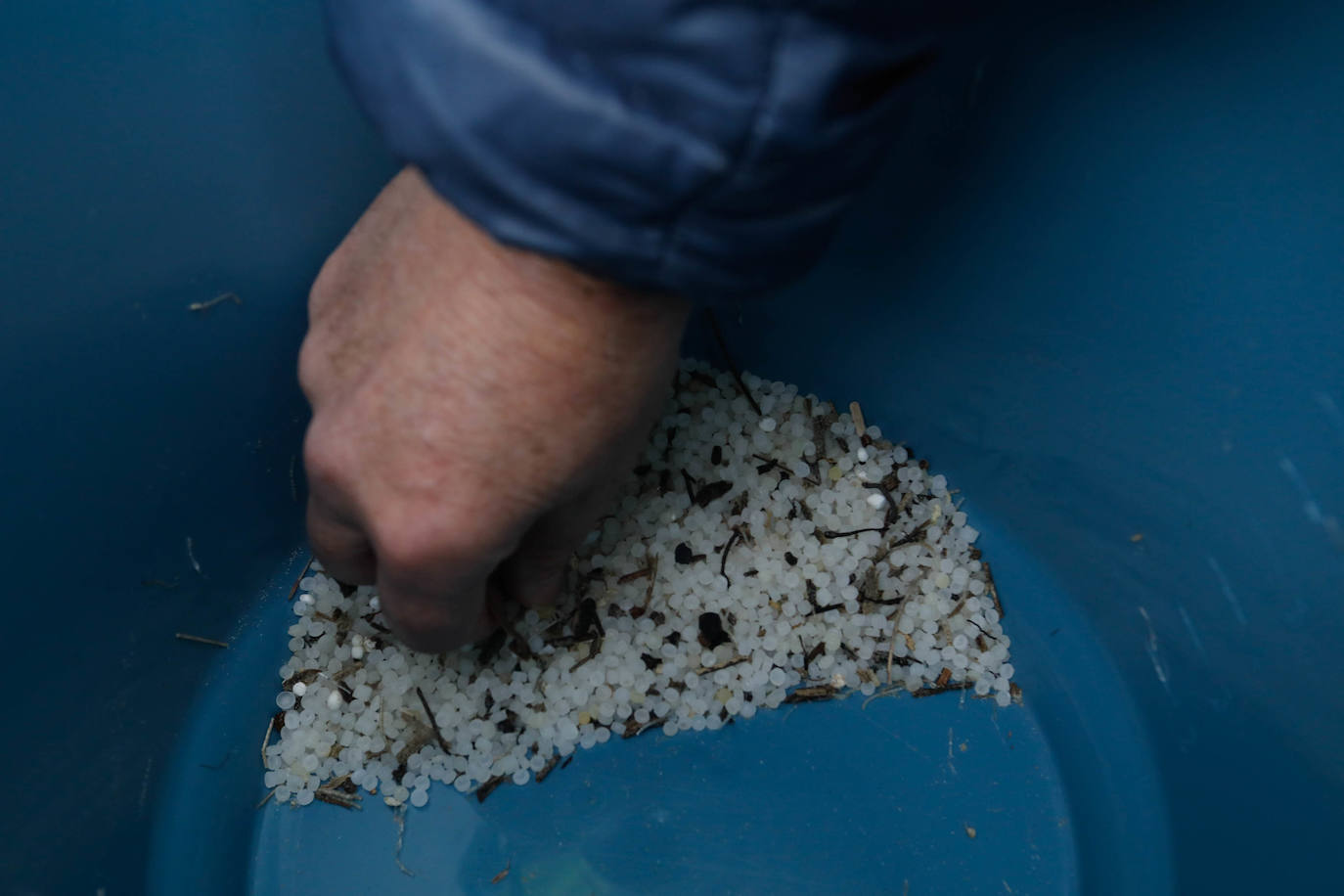 Operarios retiran los pellets o bolitas para fabricar plástico que aparecen en las playas de Asturias, tras la caída de un contenedor de un barco el pasado diciembre, esta mañana en la playa asturiana del Aguilar.